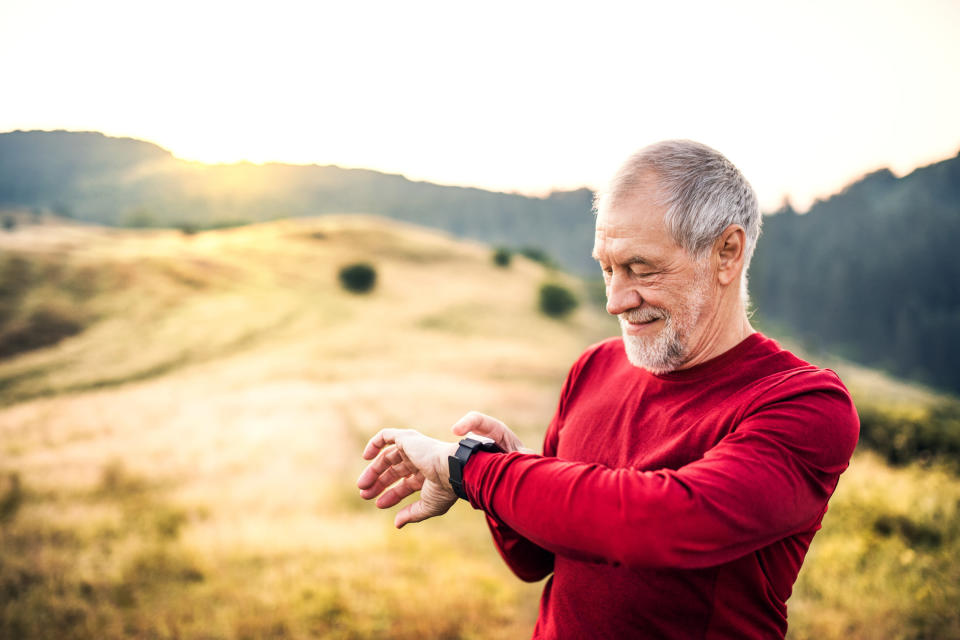 A man in running gear looks at his watch and smiles