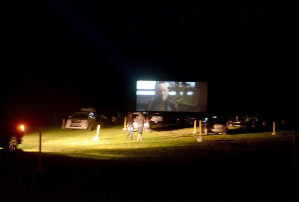 A couple walking back from the concessions stand is illuminated by the headlights of a car looking to park during the opening trailers to one of the movies shown at the Hwy 21 Drive-In on Sunday, October 2, 2016, in Beaufort.