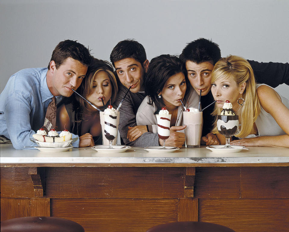 Matthew Perry, Jennifer Aniston, David Schwimmer, Courteney Cox, Matt LeBlanc, and Lisa Kudrow from Friends are drinking milkshakes with straws at a diner