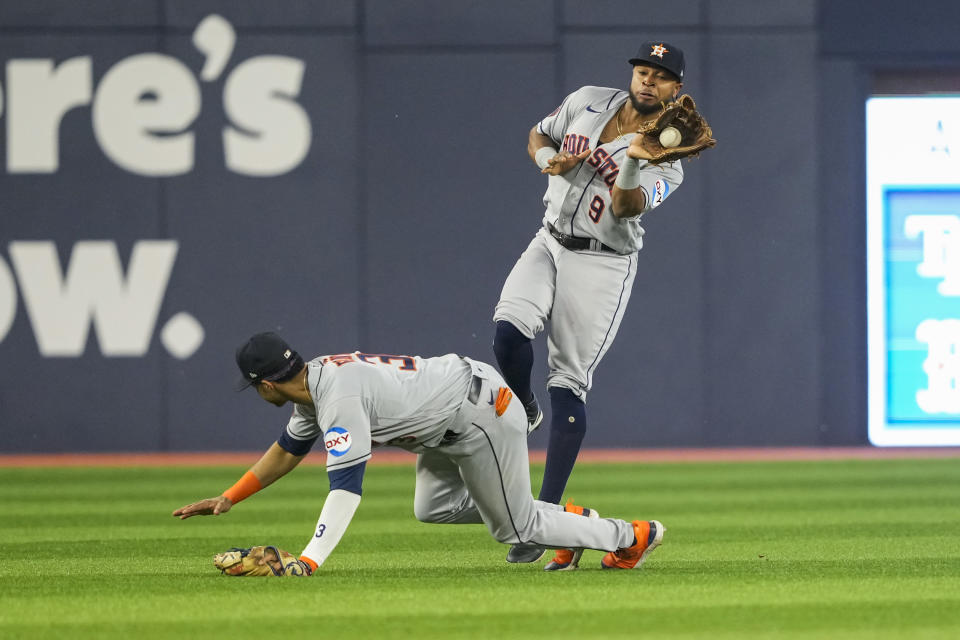 Houston Astros left fielder Corey Julks (9) leaps over teammate shortstop Jeremy Pena (3) after making a catch against Toronto Blue Jays' Daulton Varsho in sixth-inning baseball game action in Toronto, Ontario, Monday, June 5, 2023. (Andrew Lahodynskyj/The Canadian Press via AP)