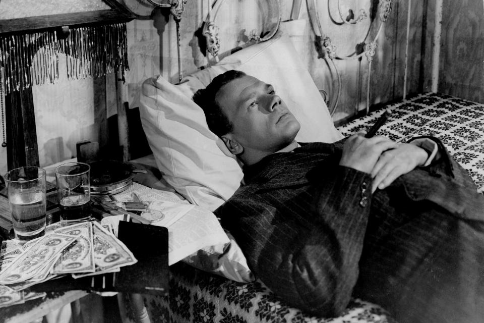 Joseph Cotten laying in bed fully dresses with open cash beside him in a scene from the film 'Shadow Of A Doubt', 1943. (Photo by Universal/Getty Images)