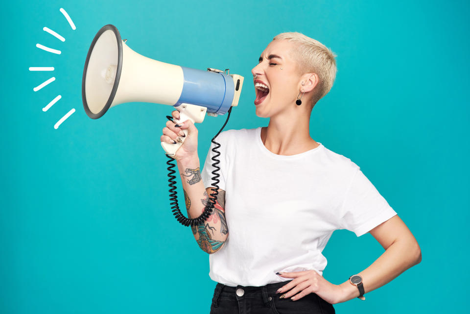 A woman holding a megaphone and screaming into it with her mouth open