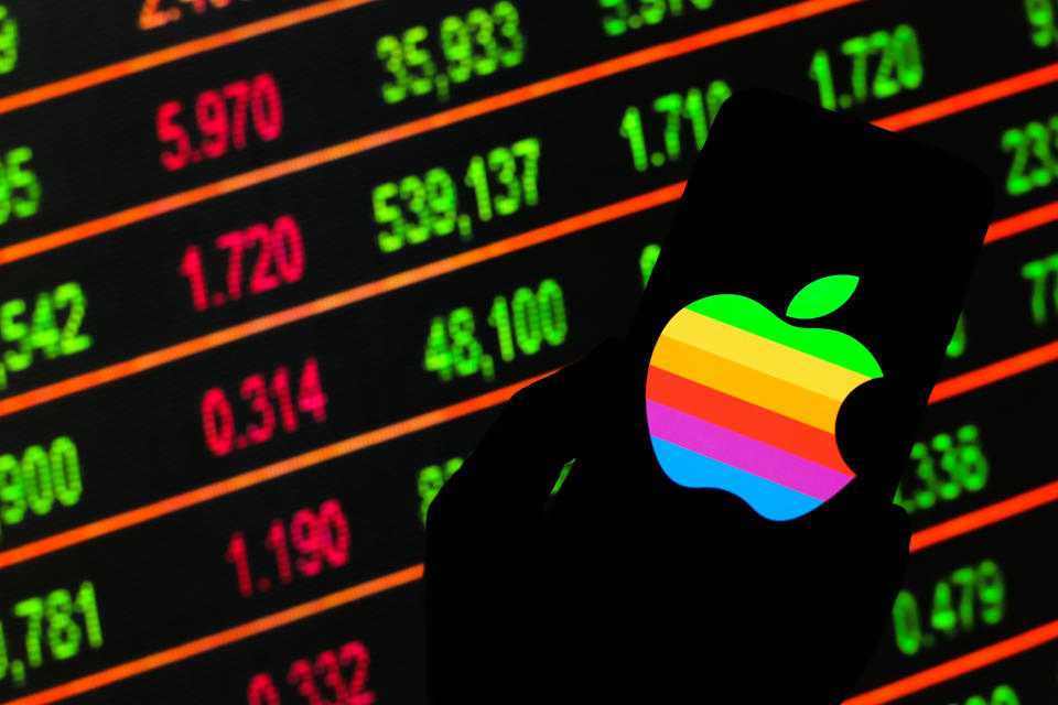 POLAND - 2020/03/13: In this photo illustration an Apple logo seen displayed on a smartphone. Stock market prices in the background as stock markets tumble all over the world. (Photo by Filip Radwanski/SOPA Images/LightRocket via Getty Images)