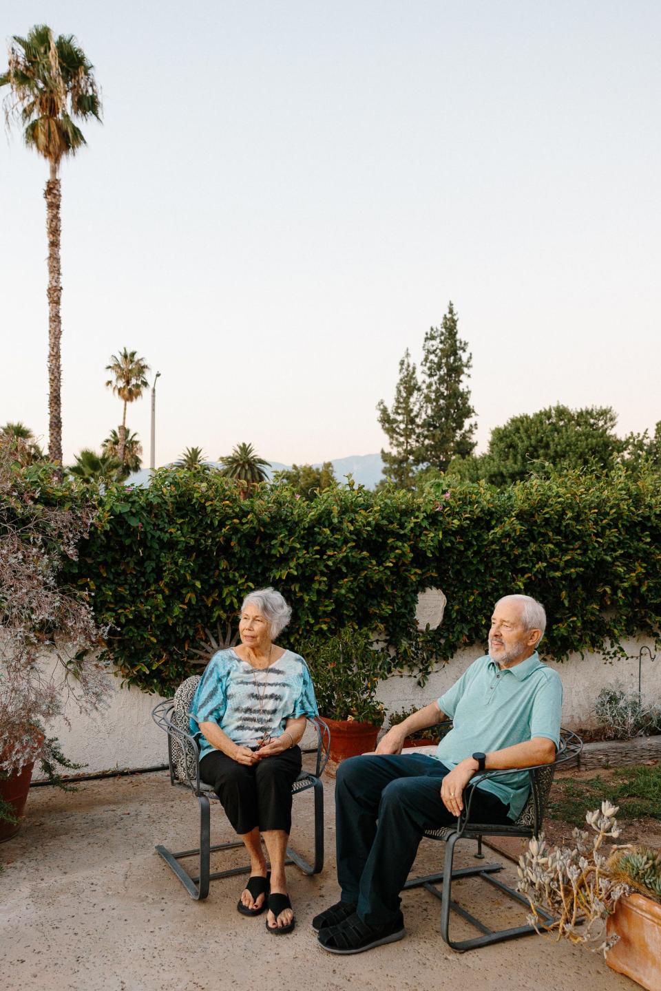 J Mailen Kootsey sitting with his wife, Lynne, outdoors with palm trees nearby.
