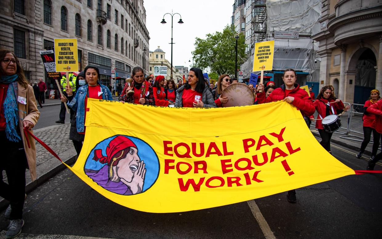 Activists march with a large banner saying, "Equal Pay for Equal Work!" during the May Day London march and rally