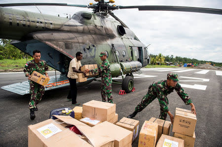 Indonesian soldiers along with a local resident unload food and medical aid in Ewer, Asmat District, in the remote region of Papua, Indonesia January 29, 2018 in this photo taken by Antara Foto. Picture taken January 29, 2018. Antara Foto/M Agung Rajasa/ via REUTERS