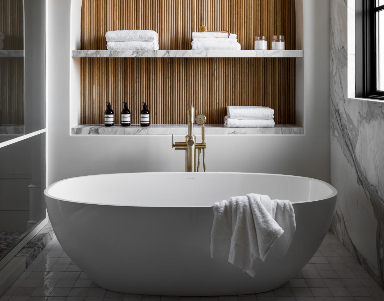  A white bathroom with wood accents and warm hardware. 