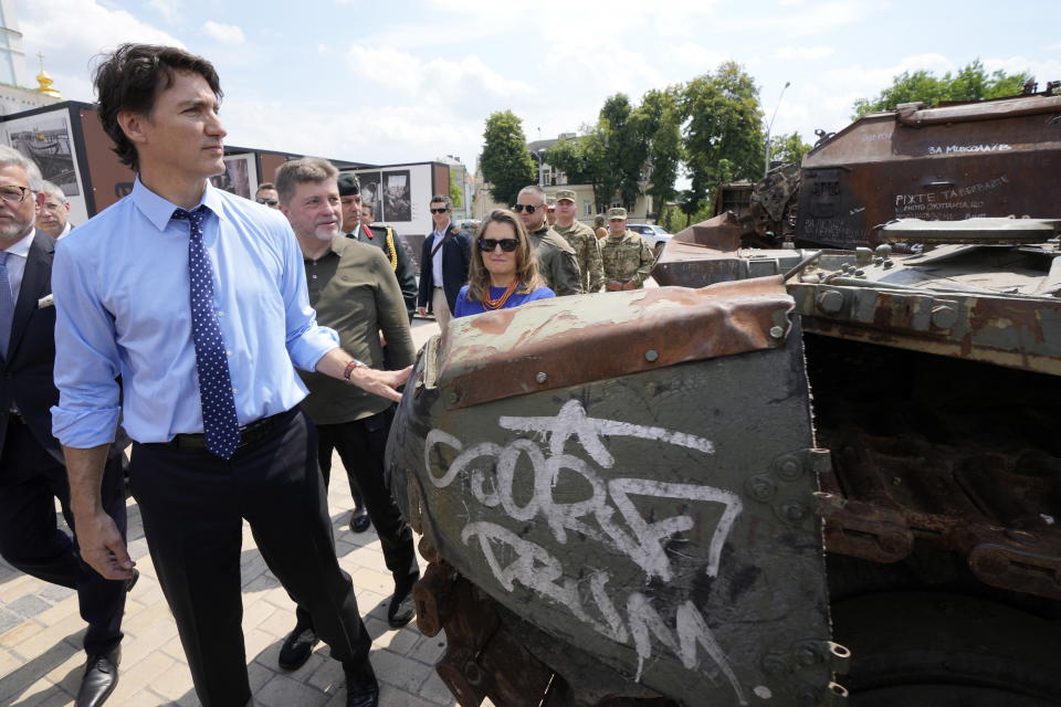 Canadian Prime Minister Justin Trudeau, left, accompanied by Deputy Prime Minister and Minister of Finance Chrystia Freeland, walks past burned out Russian tanks in Kyiv, Ukraine, Saturday, June 10, 2023. (Frank Gunn/The Canadian Press via AP)