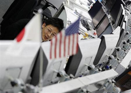 An employee of a foreign exchange trading company works behind monitors in Tokyo November 28, 2013. REUTERS/Toru Hanai