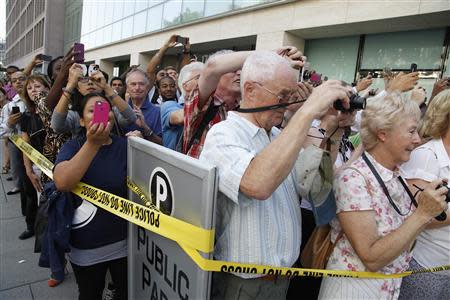 People watch U.S. President Barack Obama and Vice President Joe Biden (both not pictured) walk down the sidewalk after buying lunchat a sandwich shop near the White House in Washington, October 4, 2013. REUTERS/Jonathan Ernst