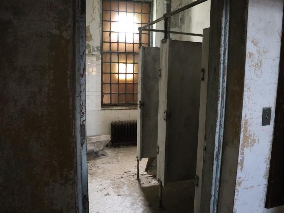 rusted bathroom stalls with a sink on the floor at ellis island hospital