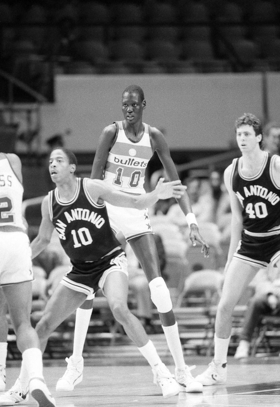 Washington Bullets center Manute Bol towers over opponents and teammates alike, during a game with the San Antonio Spurs in New York on Oct. 17, 1985.