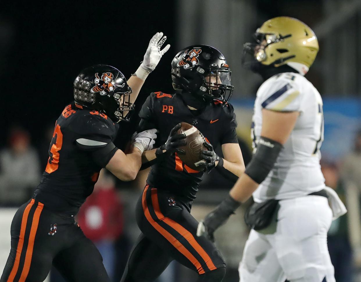 Massillon linebacker Vito McConnell, center, celebrates with Cody Fair, left, after intercepting Hoban quarterback Tylan Boykin in the first half of the OHSAA Division II state final at Tom Benson Hall of Fame Stadium, Thursday, Nov. 30, 2023, in Canton.