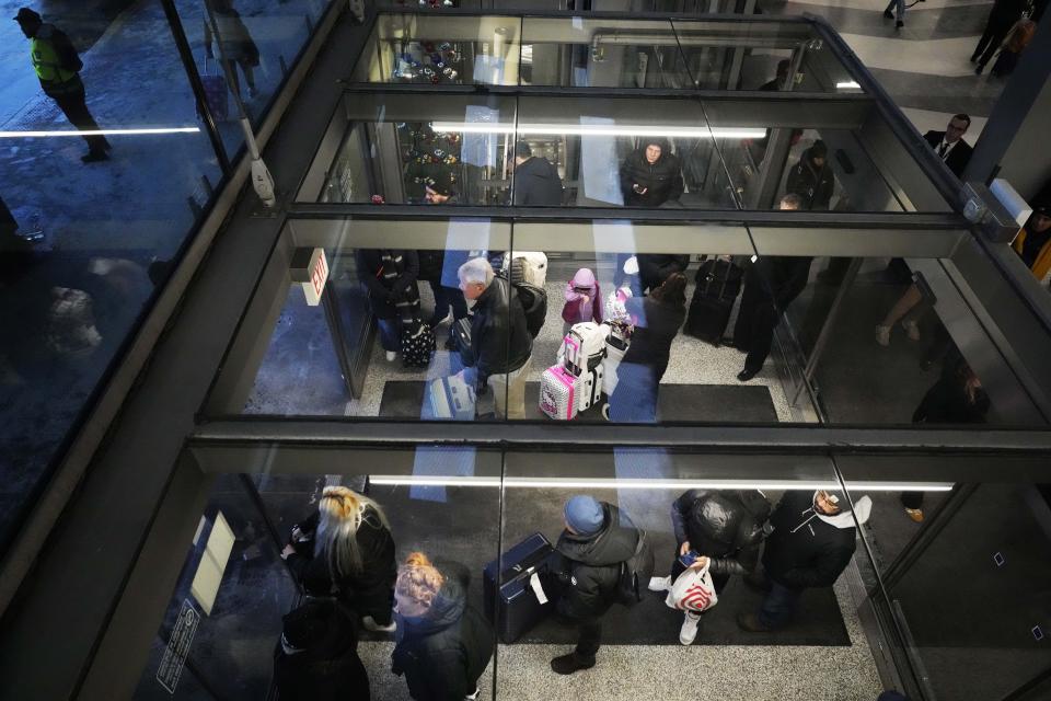 Travelers wait and look outside for an airport shuttle bus from inside of Terminal 3 as airport train doesn't run due to cold weather at the O'Hare International Airport in Chicago, Sunday, Jan. 14, 2024. Wind chill warning is in effect as dangerous cold conditions continue in the Chicago area. (AP Photo/Nam Y. Huh)