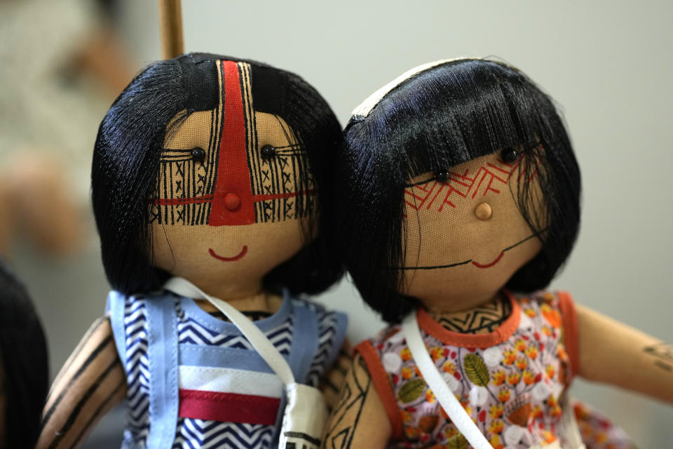 Dolls bearing faces and body paints of different Indigenous groups are displayed on a table at a sewing workshop in Rio de Janeiro, Brazil, Tuesday, May 24, 2022. Each one of them is hand sown, dressed in clothes created by Luakam Anambe, of Brazil’s Anambe Indigenous group, and carefully painted by her daughter Atyna Pora. (AP Photo/Silvia Izquierdo)