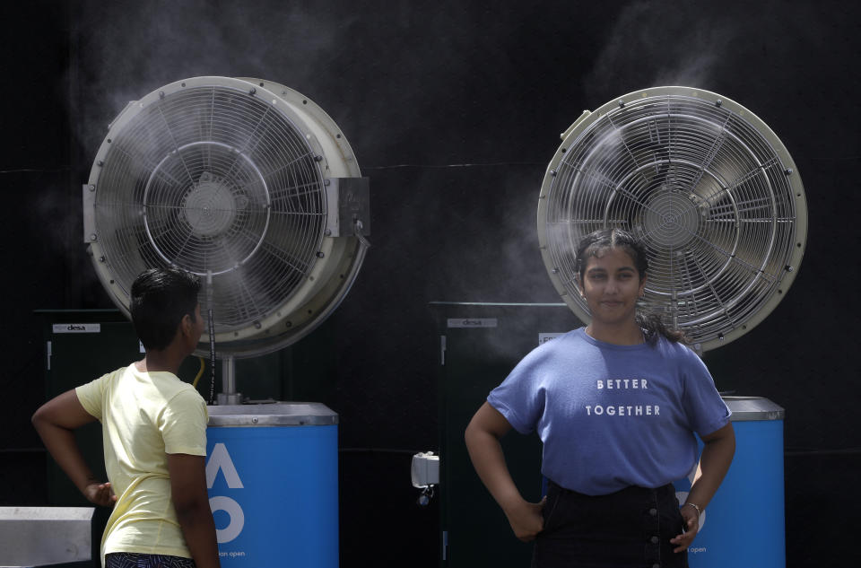 FILE - In this Friday, Jan. 25, 2019, file photo, spectators cool themselves down by water-cooling fans at the Australian Open tennis championships in Melbourne, Australia. Australia has sweltered through its hottest month on record in January and the summer of extremes continues with wildfires razing the drought-parched south while expanses of the tropical north are flooded. Australia’s Bureau of Meteorology confirmed the record heat during January as parts of the northern hemisphere have had record cold. (AP Photo/Kin Cheung, File)
