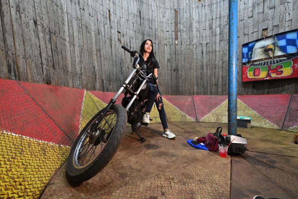 Karmila Purba, a 23 year old daredevil, sitting on a motorcycle resting at the bottom of a "Well of Death." 