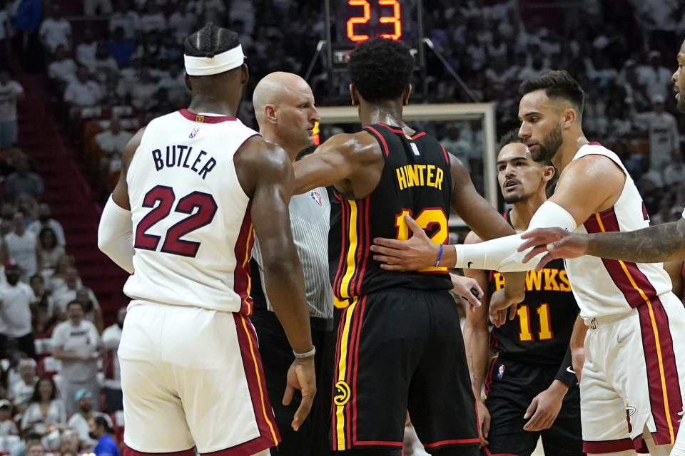 Atlanta Hawks forward De'Andre Hunter (12) stands between Miami Heat forward Jimmy Butler (22) and guard Trae Young (11) after both were called for foul during the first half of Game 1 of an NBA basketball first-round playoff series, Sunday, April 17, 2022, in Miami. (AP Photo/Lynne Sladky)
