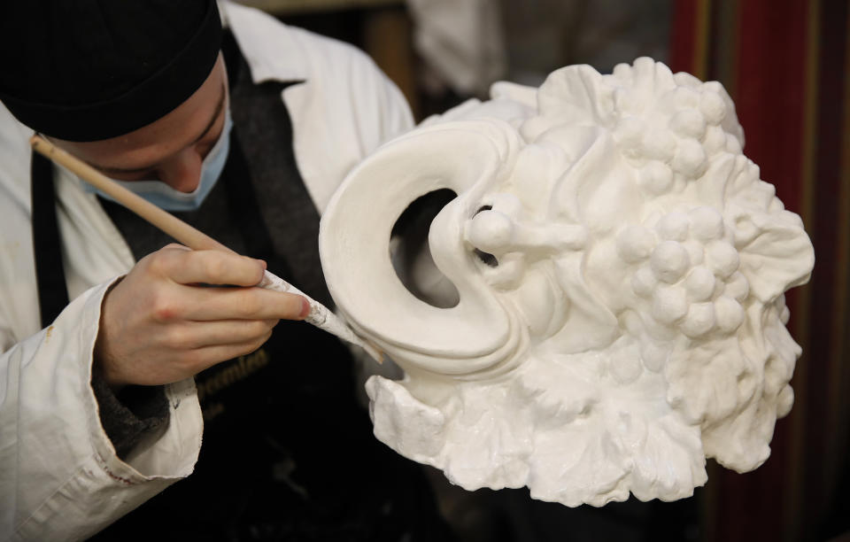 A Venetian artisan mask maker works on an item in a workshop in Venice, Italy, Saturday, Jan. 30, 2021. In another year, masks would be an accepted sign of gaiety in Venice, an accessory worn for games, parties and crowds. Since the onset of the COVID-19 pandemic face masks are worn now to protect, not amuse. (AP Photo/Antonio Calanni)