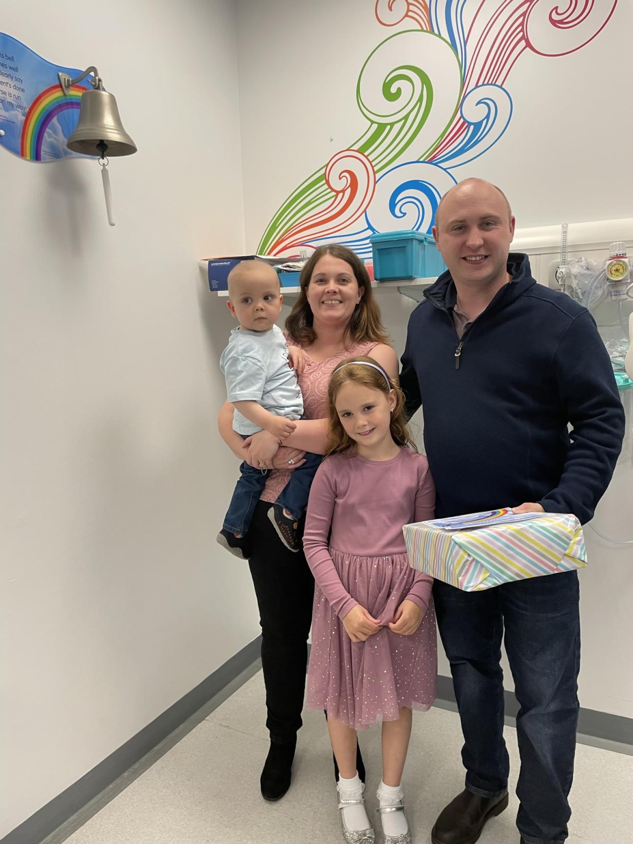 Hayley, 33, her partner, Andy, 30, Jessica, 7, and Jaxon, 2, ring the bell at hospital to commemorate his cancer-free diagnosis. (Hayley Barnes/SWNS)