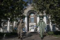 In this photo taken on Friday, May 1, 2020, firefighters in special protective suits spray chlorine in front of a hospital in Pochaiv, Ukraine. Ukraine's troubled health care system has been overwhelmed by COVID-19, even though it has reported a relatively low number of cases. (AP Photo/Evgeniy Maloletka)