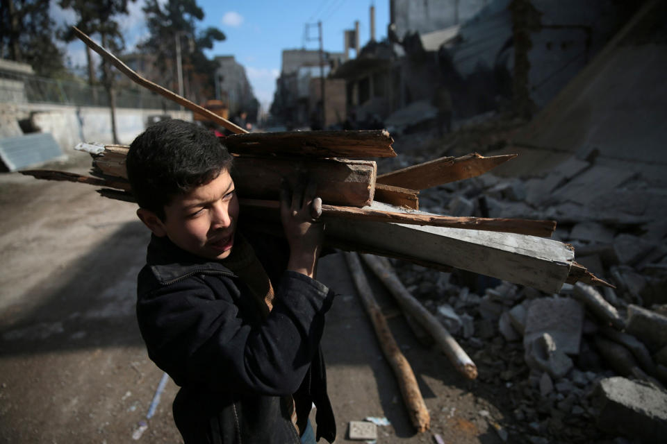 A boy collects firewood in besieged Douma, Syria