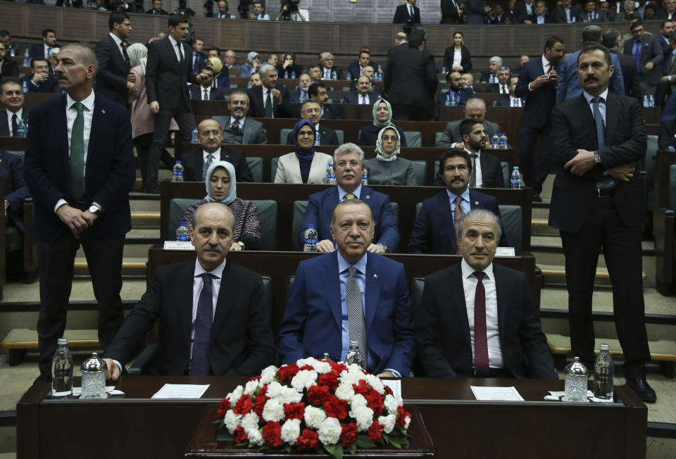 Flanked by his aides and standing security officials, Turkey's President Recep Tayyip Erdogan waits to address his supporters at the parliament, in Ankara, Turkey, Tuesday, Oct. 30, 2018. Erdogan said the Turkish prosecutor repeated to his Saudi counterpart Turkey's extradition request of 18 suspects detained in Saudi Arabia for the Oct. 2 killing to be put on trial in Istanbul. (Presidential Press Service via AP, Pool)