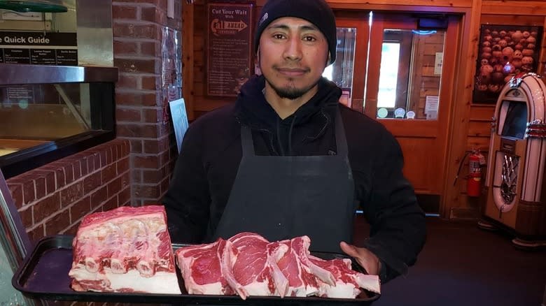 Texas Roadhouse meat cutter holding a tray of steaks
