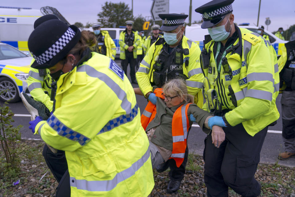 Police officers carry away a protester who had glued herself to a slip road at Junction 4 of the A1(M), near Hatfield, where climate activists carried out a further action after demonstrations which took place last week across junctions in Kent, Essex, Hertfordshire and Surrey. Picture date: Monday September 20, 2021.