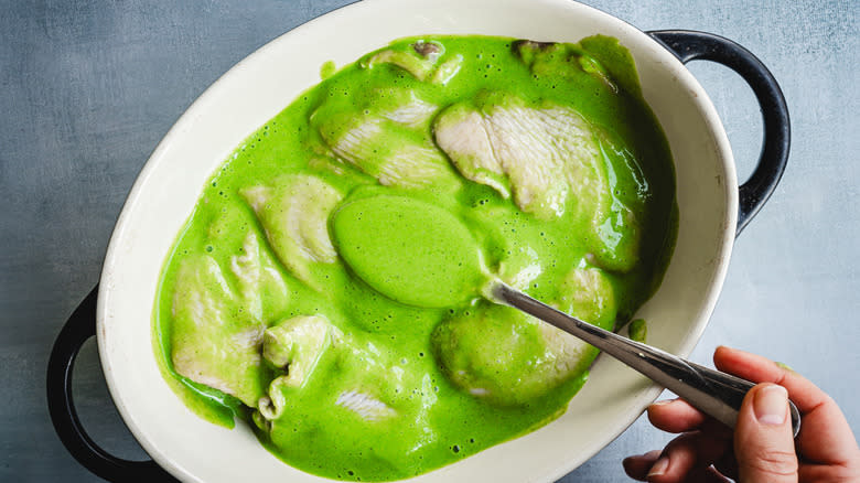 Spooning green herb marinade on chicken dish