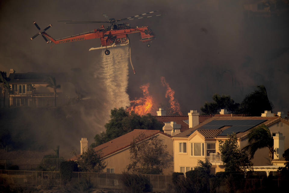 FILE - In this Oct. 11, 2019, file photo, a helicopter drops water while battling a wildfire called the Saddle Ridge Fire in Porter Ranch, Calif. Fire officials say a destructive fire that broke out on the edge of Los Angeles began beneath a high-voltage transmission tower. The destructive fire that broke out on the edge of Los Angeles began beneath a high-voltage transmission tower owned by Southern California Edison, fire officials said Monday, Oct. 14, 2019. (AP Photo/Noah Berger, File)