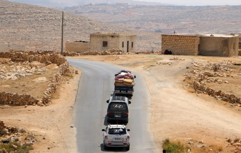 Displaced Syrians fleeing regime and Russian air strikes ride in vehicles with their belongings near a camp in Kafr Lusin close to the border with Turkey