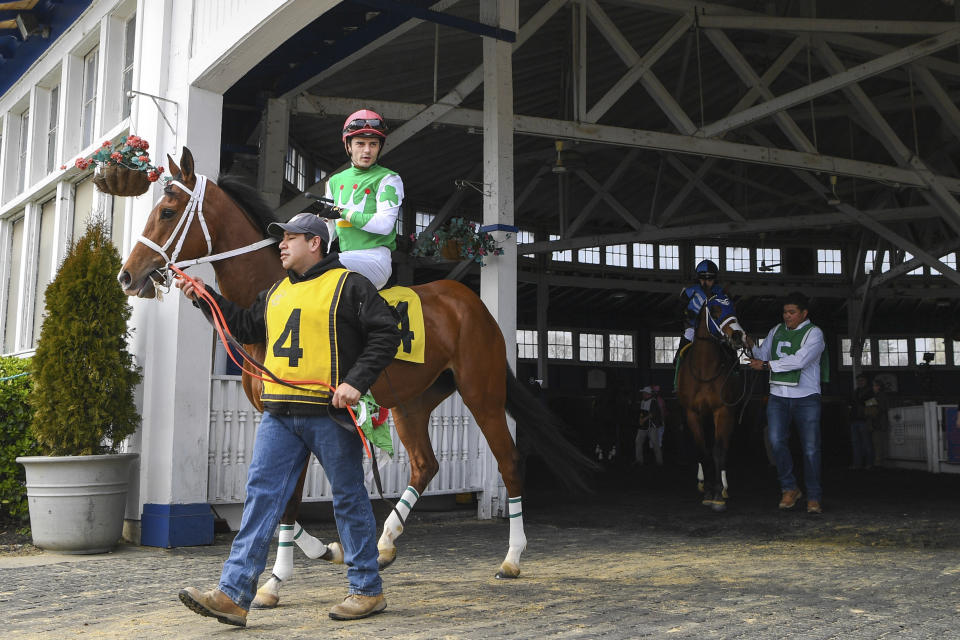 Lady Banba (4) ridden by jockey Sheldon Russell is lead out of the paddock before a horse race at Laurel Park Race Track, an event that allowed no spectators, Saturday, March 14, 2020, in Laurel, Md. While most of the sports world is idled by the coronavirus pandemic, horse racing runs on. (AP Photo/Terrance Williams)