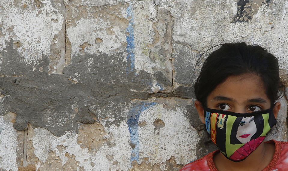 A Palestinian girl wear a face mask during a lockdown imposed following the discovery of coronavirus cases in the Gaza Strip, Thursday, Aug. 27, 2020. On Wednesday Gaza's Hamas rulers extended a full lockdown in the Palestinian enclave for three more days as coronavirus cases climbed after the detection this week of the first community transmissions of the virus in the densely populated, blockaded territory. (AP Photo/Hatem Moussa)