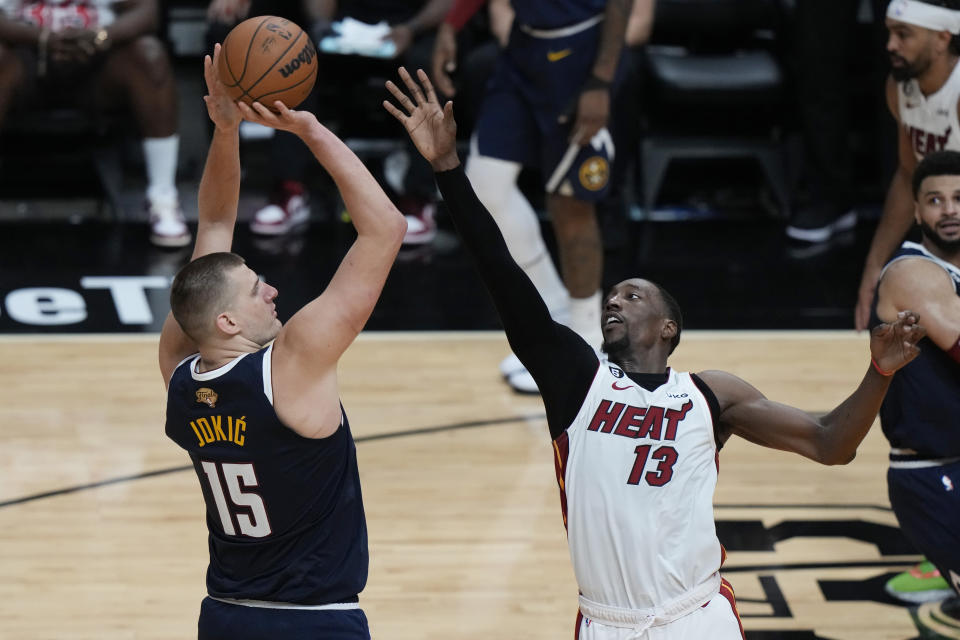 Denver Nuggets center Nikola Jokic (15) aims a three-point shot as Miami Heat center Bam Adebayo (13) defends during the second half of Game 4 of the basketball NBA Finals, Friday, June 9, 2023, in Miami. (AP Photo/Lynne Sladky)