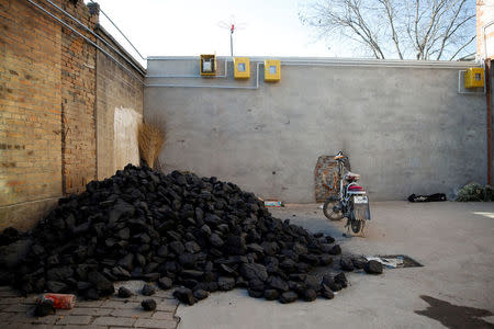 A pile of coal is seen underneath newly installed gas pipes in a courtyard in the village of Heqiaoxiang outside of Baoding, Hebei province, China, December 5, 2017. REUTERS/Thomas Peter