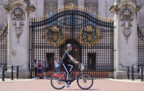 A man rides a city bike outside Buckingham Palace, as people enjoy the good weather in London, Sunday May 31, 2020. The public are being reminded to practice social distancing following the relaxation of coronavirus lockdown restrictions in England. (Dominic Lipinski/PA via AP)