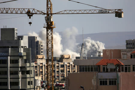 A construction crane is seen as smoke rises from Yarmouk Palestinian camp in Damascus, Syria April 21, 2018. REUTERS/Ali Hashisho