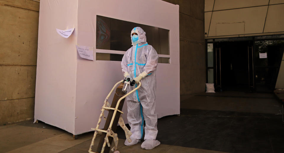 A healthcare worker with an oxygen tank on a trolley.