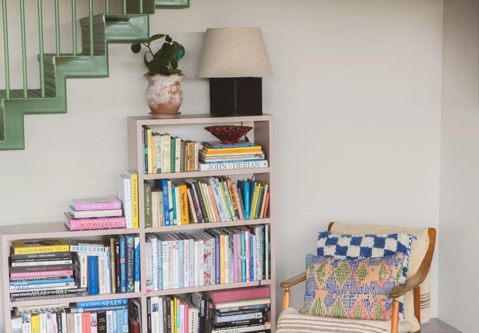 a bookshelf with books and a lamp and a chair with coat paints nada colour on the walls