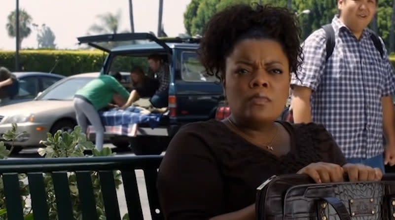 Shirley sitting on a bench while Abed delivers a baby in an SUV in the background in "Community"