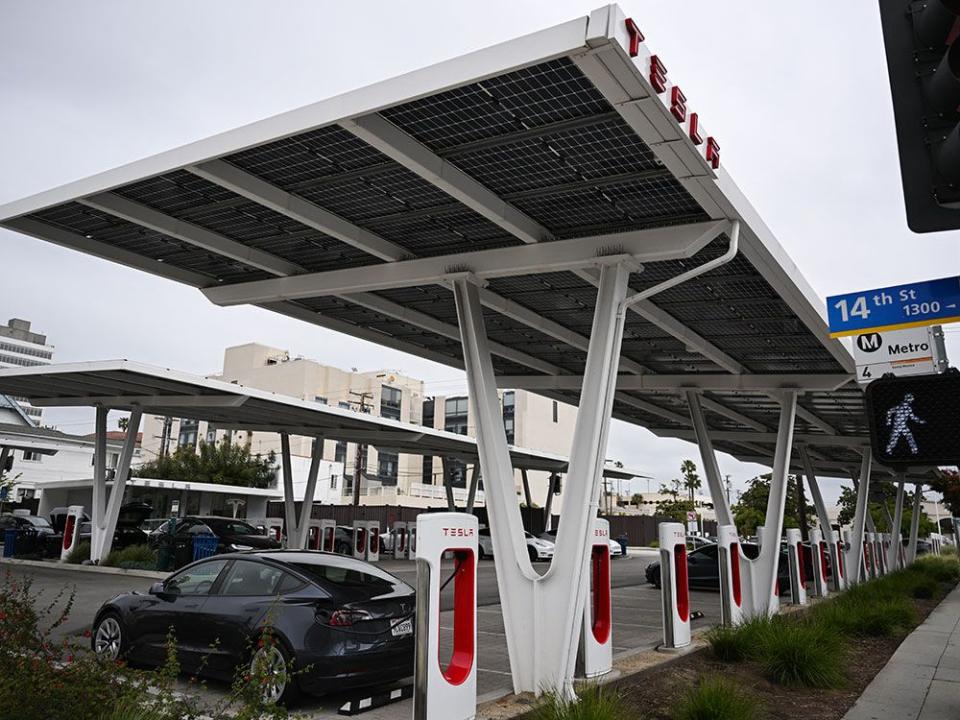  Tesla electric vehicles charge on EV charging stations beneath solar panels at a Tesla Supercharger location in Santa Monica, California.