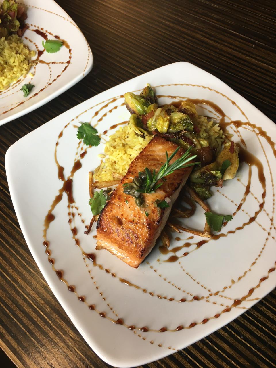 Pan-seared salmon with olive and caper tapenade, curry rice, sautéed courgettes and peppers at The Black Jockeys Lounge.