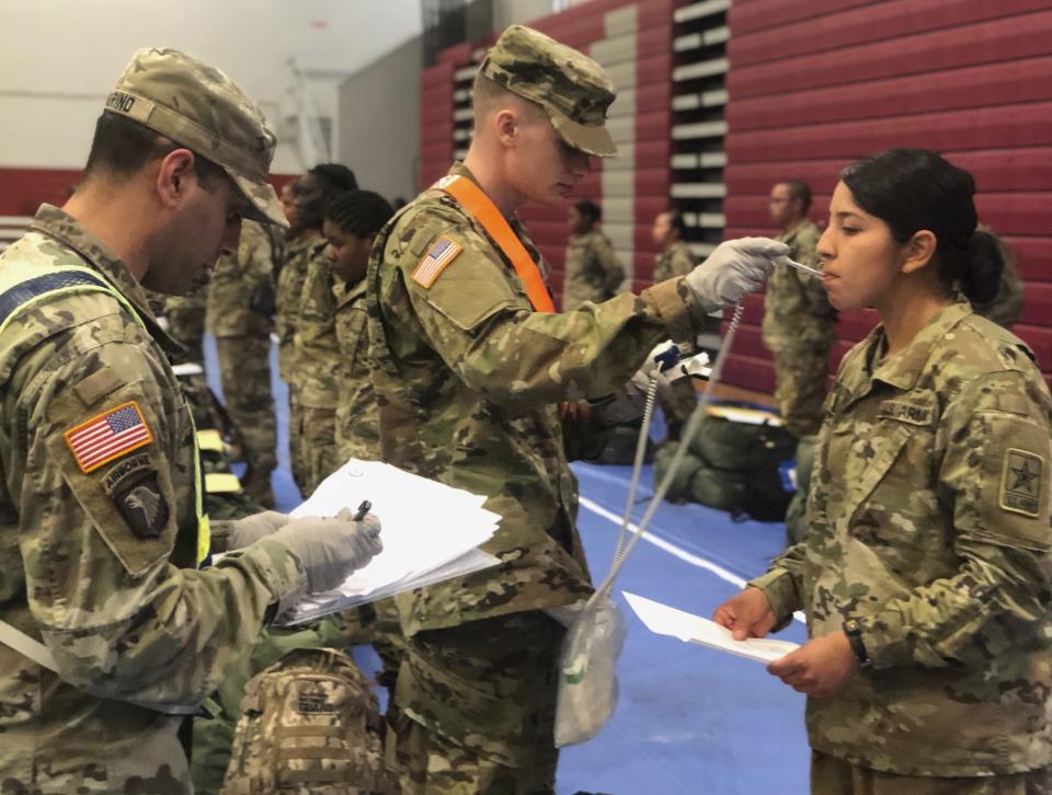 In this image provided by the U.S. Army, recent Army basic combat training graduates have their temperatures taken as they arrive at Fort Lee, Va, on March 31, 2020, after being transported using sterilized buses from Fort Jackson, S.C. (U.S. Army via AP)