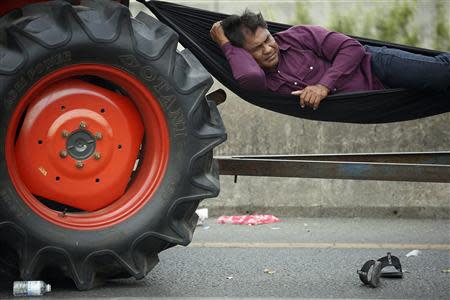 A rice farmer sleeps in a hammock attached to his tractor on a highway where farmers spent a night in Ayutthaya province February 21, 2014. REUTERS/Damir Sagolj