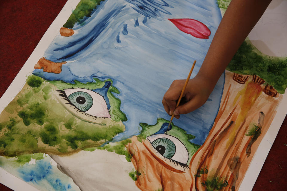 An Indian schoolgirl creates an artwork for environment awareness in Prayagraj, India , Friday, Aug. 9, 2019. More than a million Indians planted saplings as part of a government campaign to tackle climate change and improve environment in the country’s most populated state. (AP Photo/Rajesh Kumar Singh)