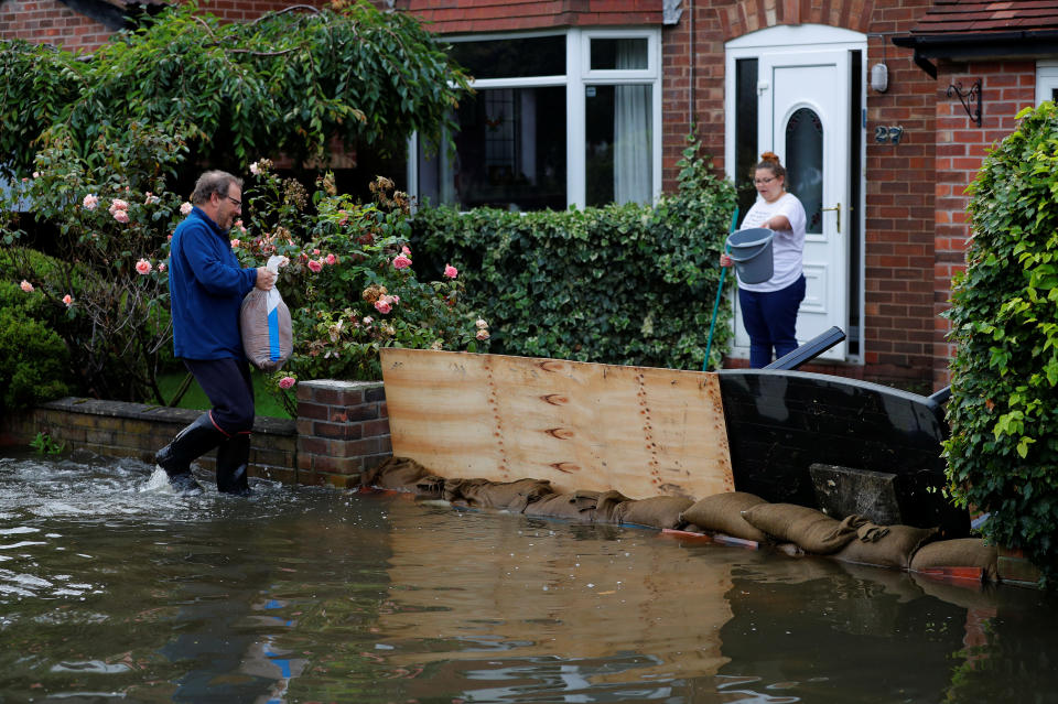 A man tries to board up his drive to prevent rising flood water from entering his house in the Sale area of Manchester, Britain, July 31, 2019. REUTERS/Phil Noble