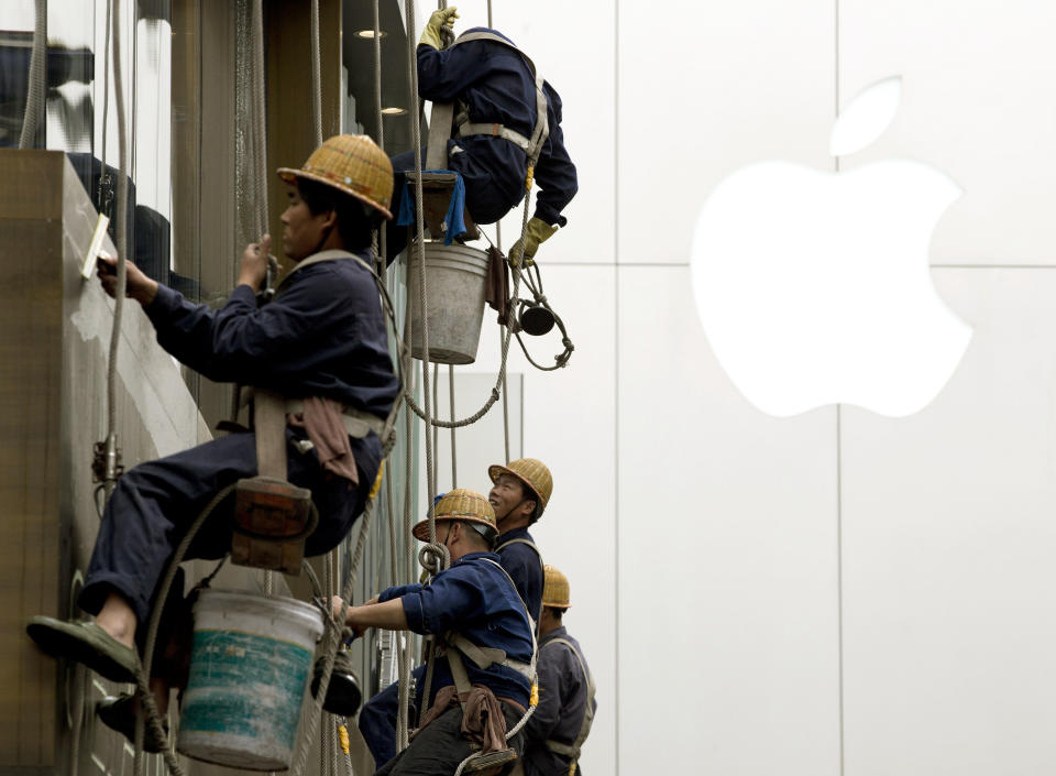 Workers clean windows near Apple's retail store in Beijing, China Thursday, April 10, 2014. China reported an unexpected contraction in exports in March, raising the danger of job losses as Beijing tries to overhaul its slowing economy. (AP Photo/Andy Wong)