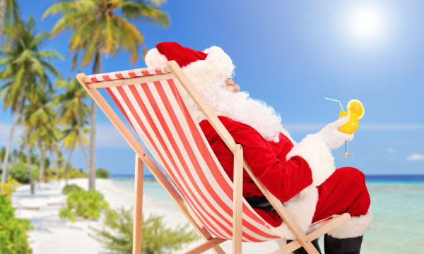 Santa Claus lying on a chair and drinking orange cocktail, enjoying on a sunny day, on a beach