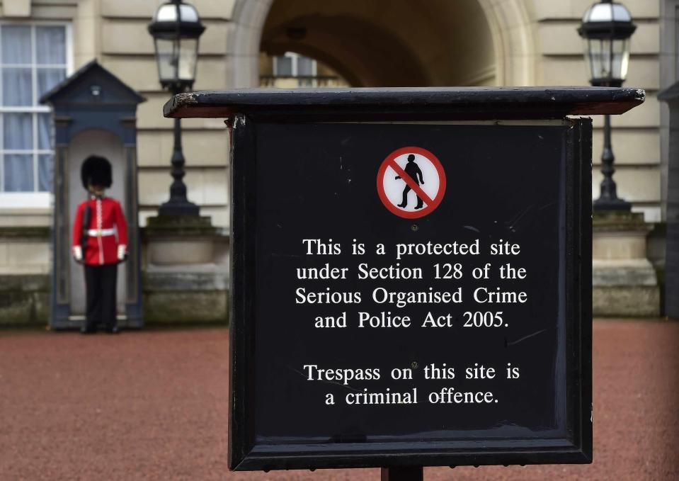 An sentry is seen standing on duty behind a security notice in the forecourt of Buckingham Palace in central London, October 24, 2014. A police officer was arrested on Thursday as part of an investigation into the discovery of ammunition in personal lockers in a police building on the grounds of Buckingham Palace, Scotland Yard said. The officer, who has not been identified, is from the unit responsible for protecting the Royal Household and normally works in a protection role, although he is not assigned to guard any individual member of the Royal Family. REUTERS/Toby Melville (BRITAIN - Tags: SOCIETY ROYALS)